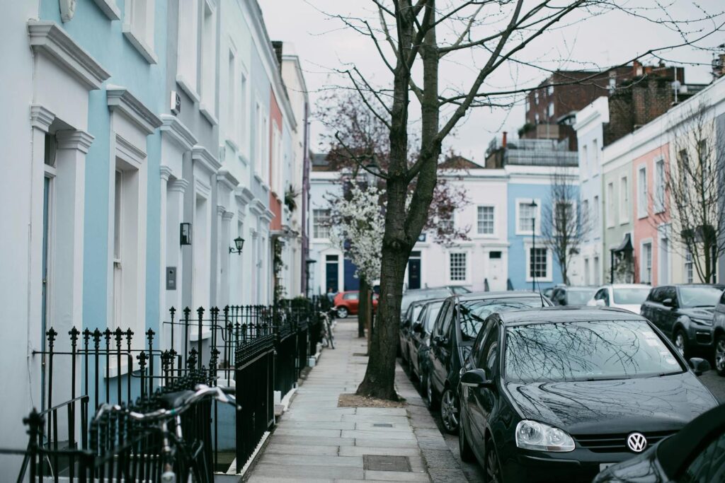 A picturesque street in London featuring pastel row houses and parked cars, perfect for urban exploration.