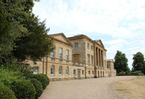 a large building with trees in front of it with Basildon Park in the background